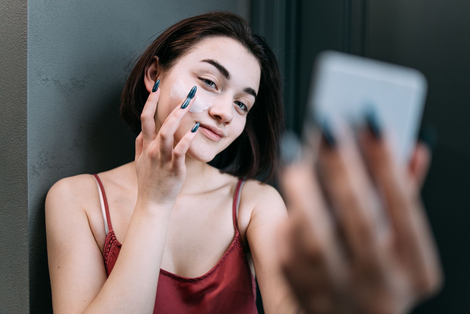 Woman applying moisturizer while looking in a mirror