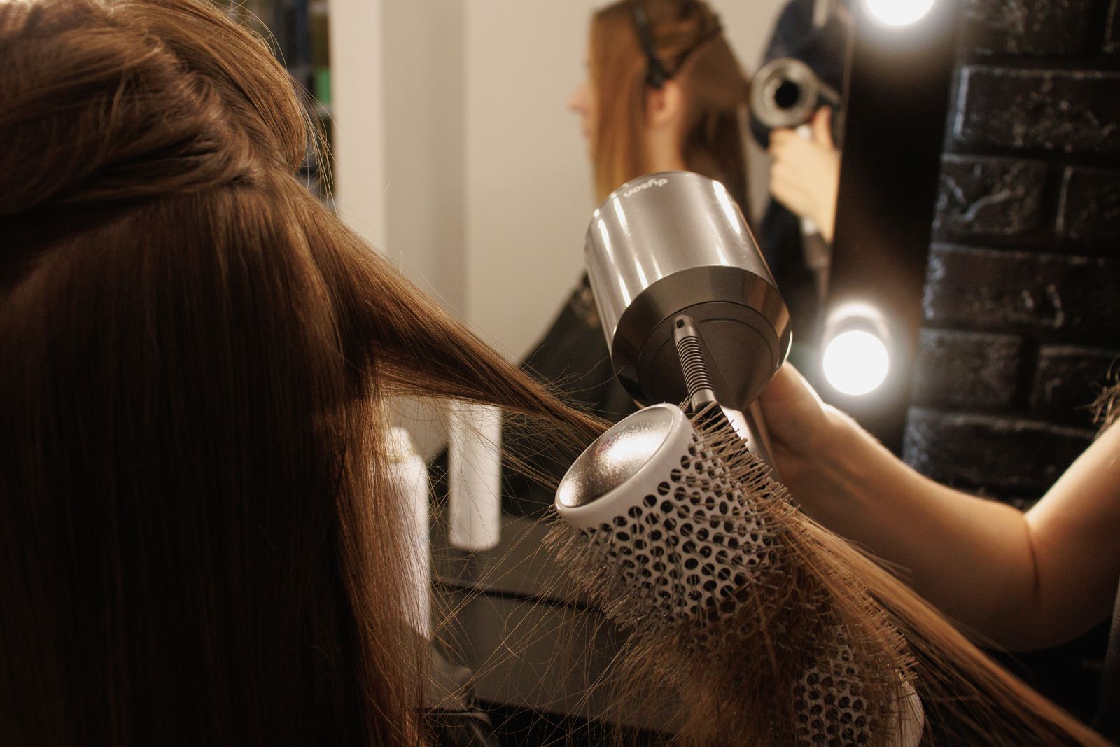 Stylist blow-drying hair with a round brush
